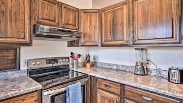 A kitchen with wooden cabinets, a stainless steel range, a built-in oven, a coffee maker, and a toaster.