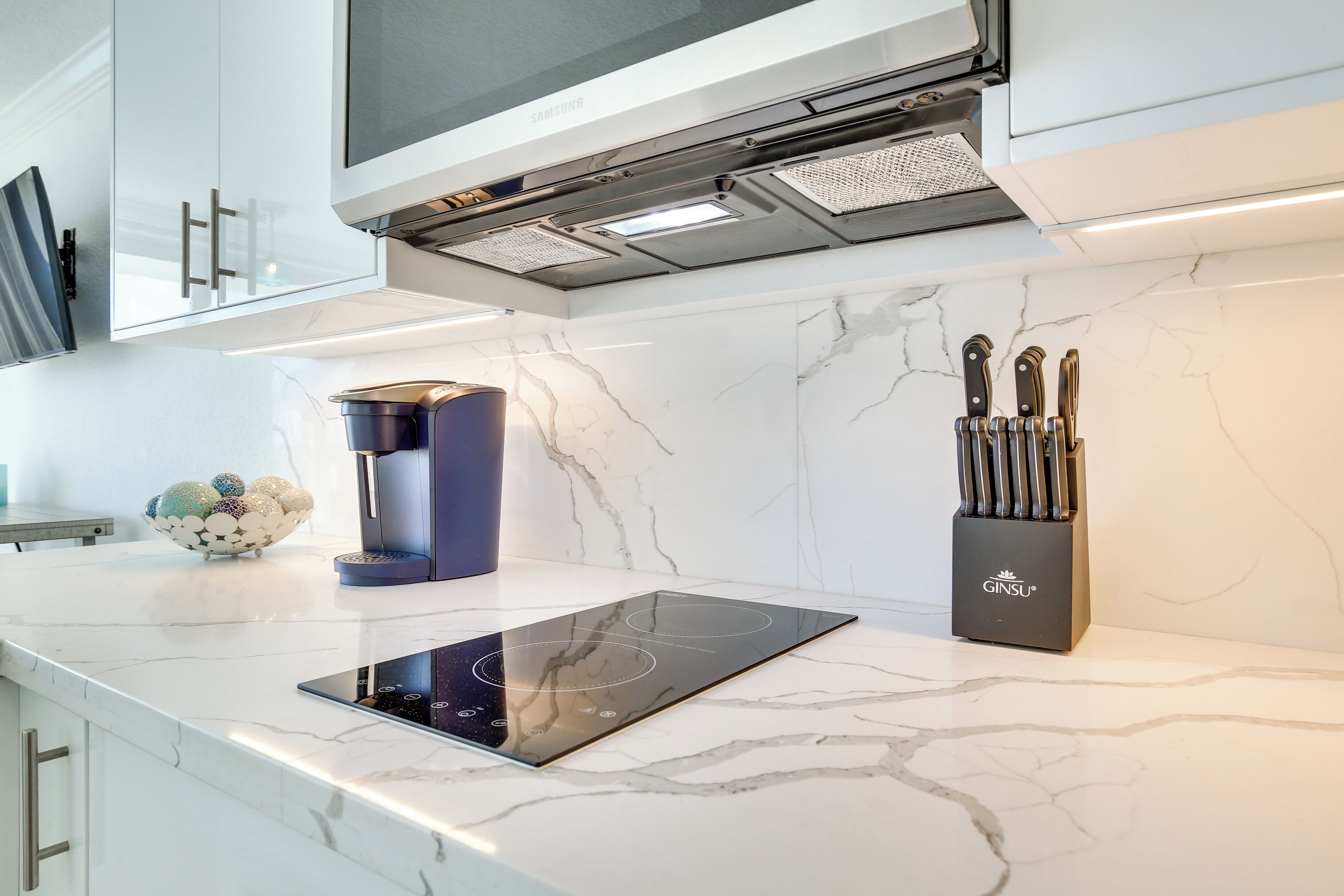 A modern kitchen with a built-in induction cooktop, a coffee machine, and a knife block.