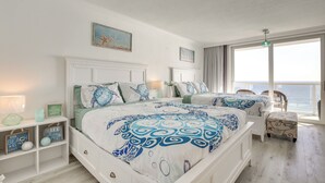 Une chambre avec un grand lit, deux tables de chevet, une commode et une vue sur l’océan.