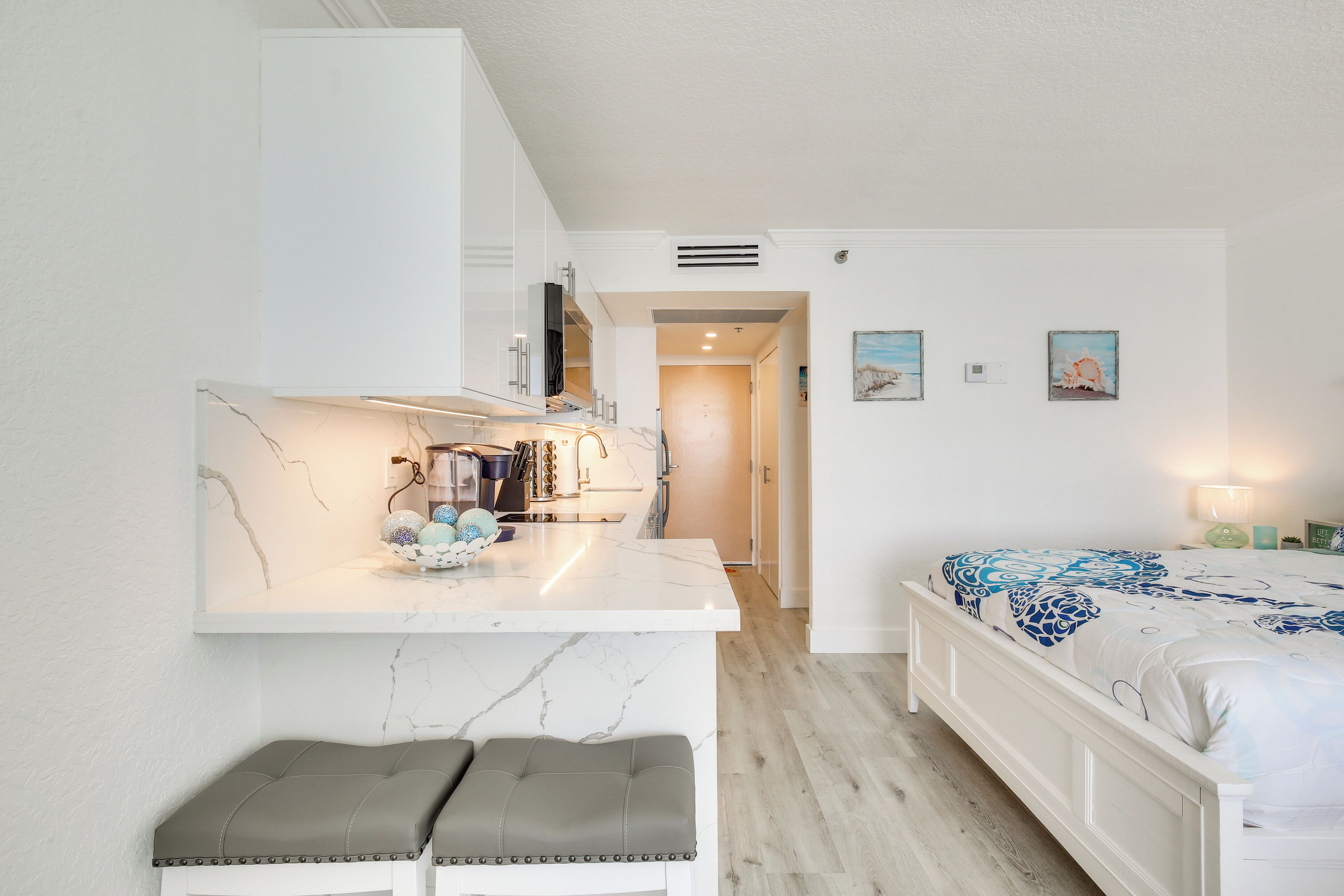 Een slaapkamer met een bed, nachtkastje en een zithoek met twee krukken.
