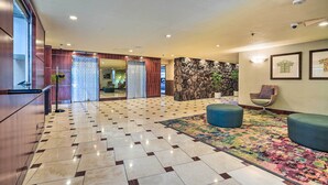 A spacious lobby with a patterned floor, a reception desk, a seating area with a colorful rug, and a stone wall. - Centrally Located Vacation Rental in Waikiki! (Honolulu)