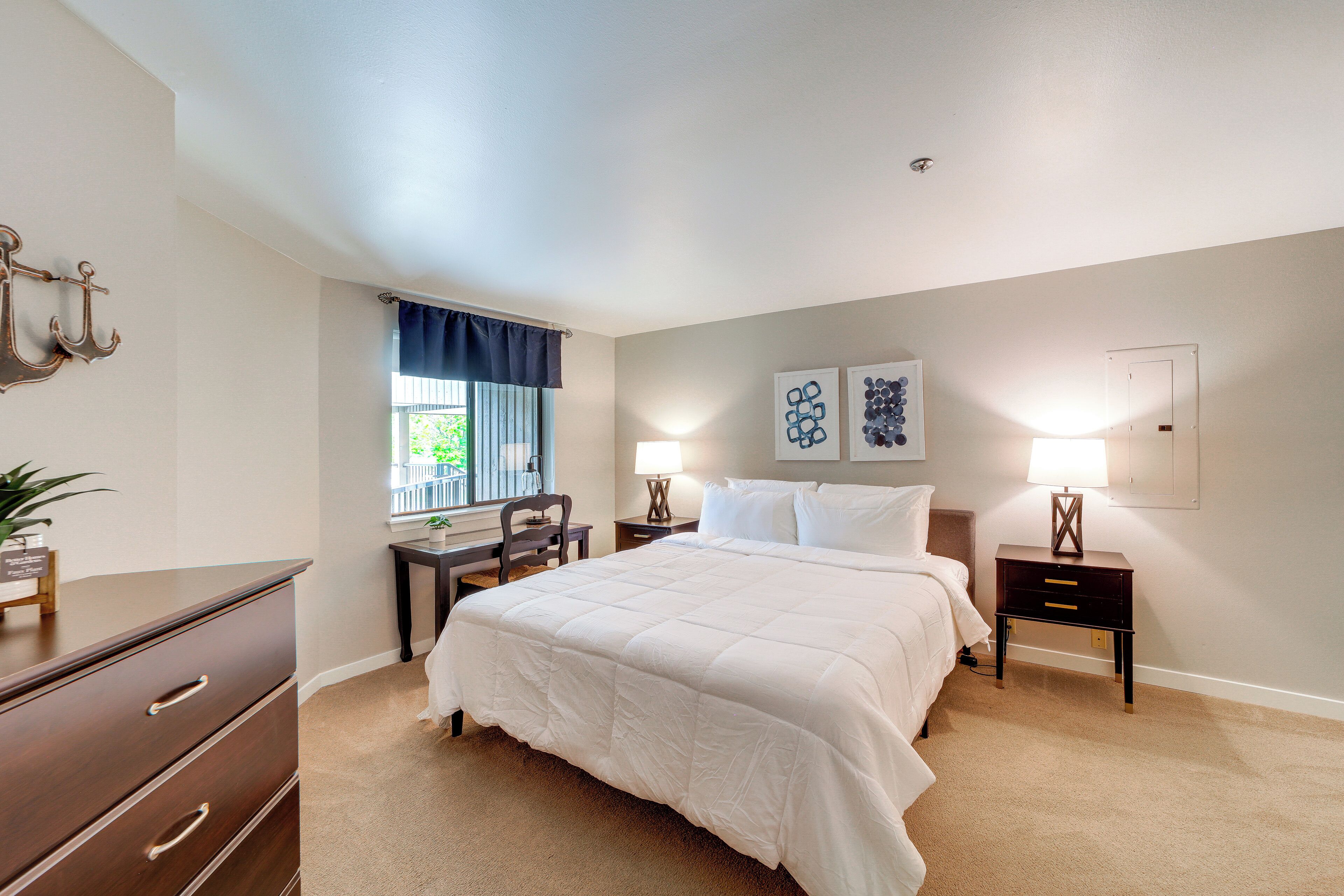 A bedroom with a bed, bedside tables, a desk, and a chair.