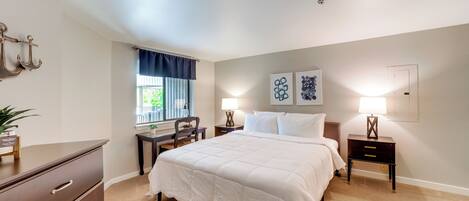A bedroom with a bed, bedside tables, a desk, and a chair.