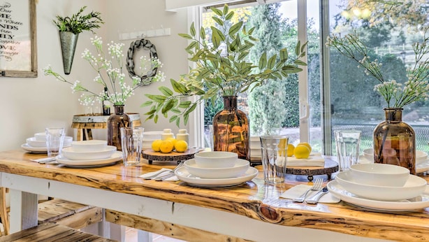A dining table set with white plates, glasses, and a centerpiece of greenery. - Modern Home in Napa Area w/ Hot Tub & Game Room! (Petaluma)