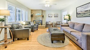 A living room with a fireplace, two sofas, a coffee table, and a ceiling fan. - Modern Home in Napa Area w/ Hot Tub & Game Room! (Petaluma)