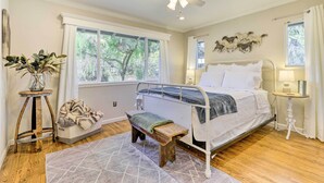 A bedroom with a bed, a bench, a bedside table, a floor lamp, a ceiling fan, and a window with curtains. - Modern Home in Napa Area w/ Hot Tub & Game Room! (Petaluma)