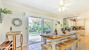 A kitchen with a wooden table and benches, a ceiling fan, and a view of the backyard. - Modern Home in Napa Area w/ Hot Tub & Game Room! (Petaluma)