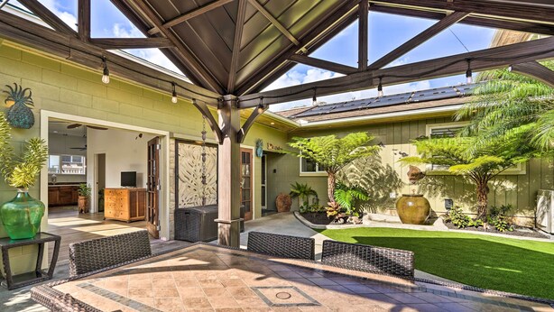 A covered patio with a dining area, a green lawn, and a view of the backyard.