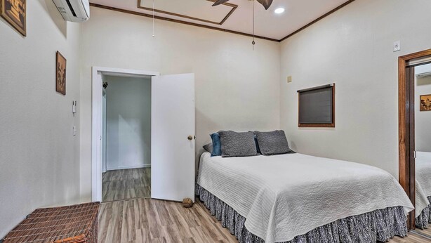 Ein Schlafzimmer mit Bett, Deckenventilator und einer Tür zu einem weiteren Raum.