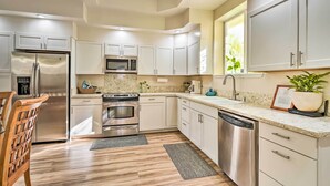 A modern kitchen with stainless steel appliances, white cabinetry, and a granite countertop.
