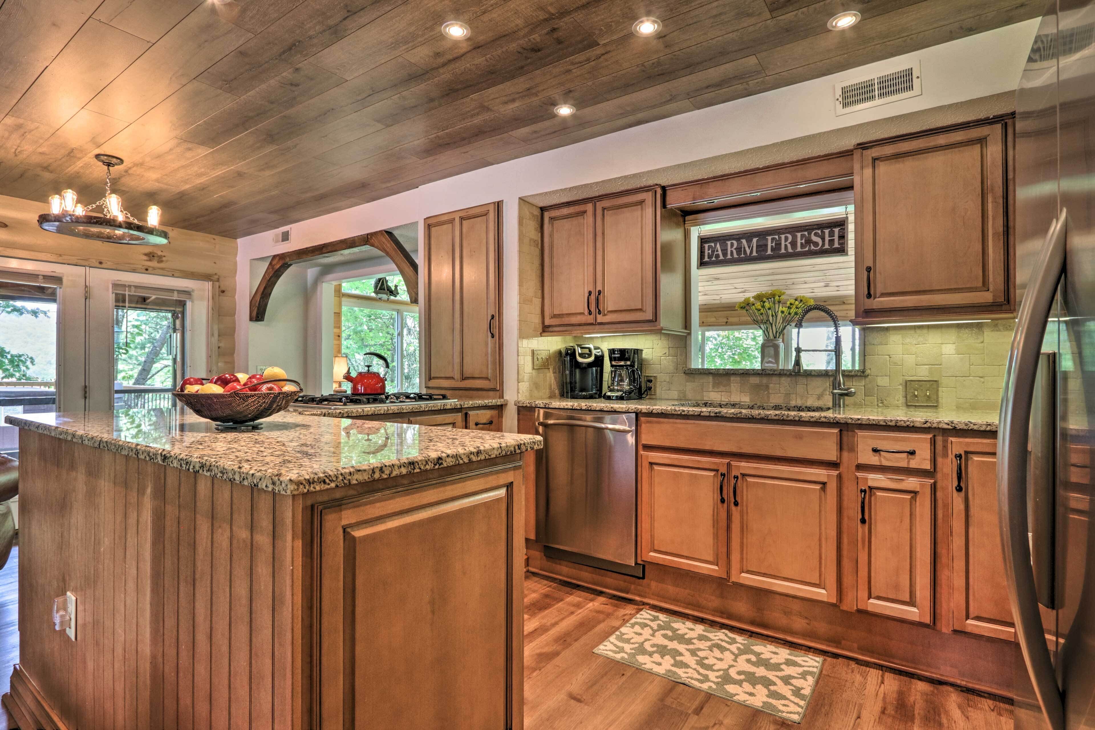 Una cocina con armarios de madera, encimeras de granito, electrodomésticos de acero inoxidable y vistas al exterior.