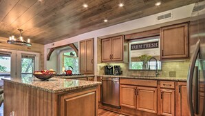 A kitchen with wooden cabinets, granite countertops, stainless steel appliances, and a view of the outdoors. - Mtn-view Cabin w/ Hot Tub in Sevierville! (Sevierville)