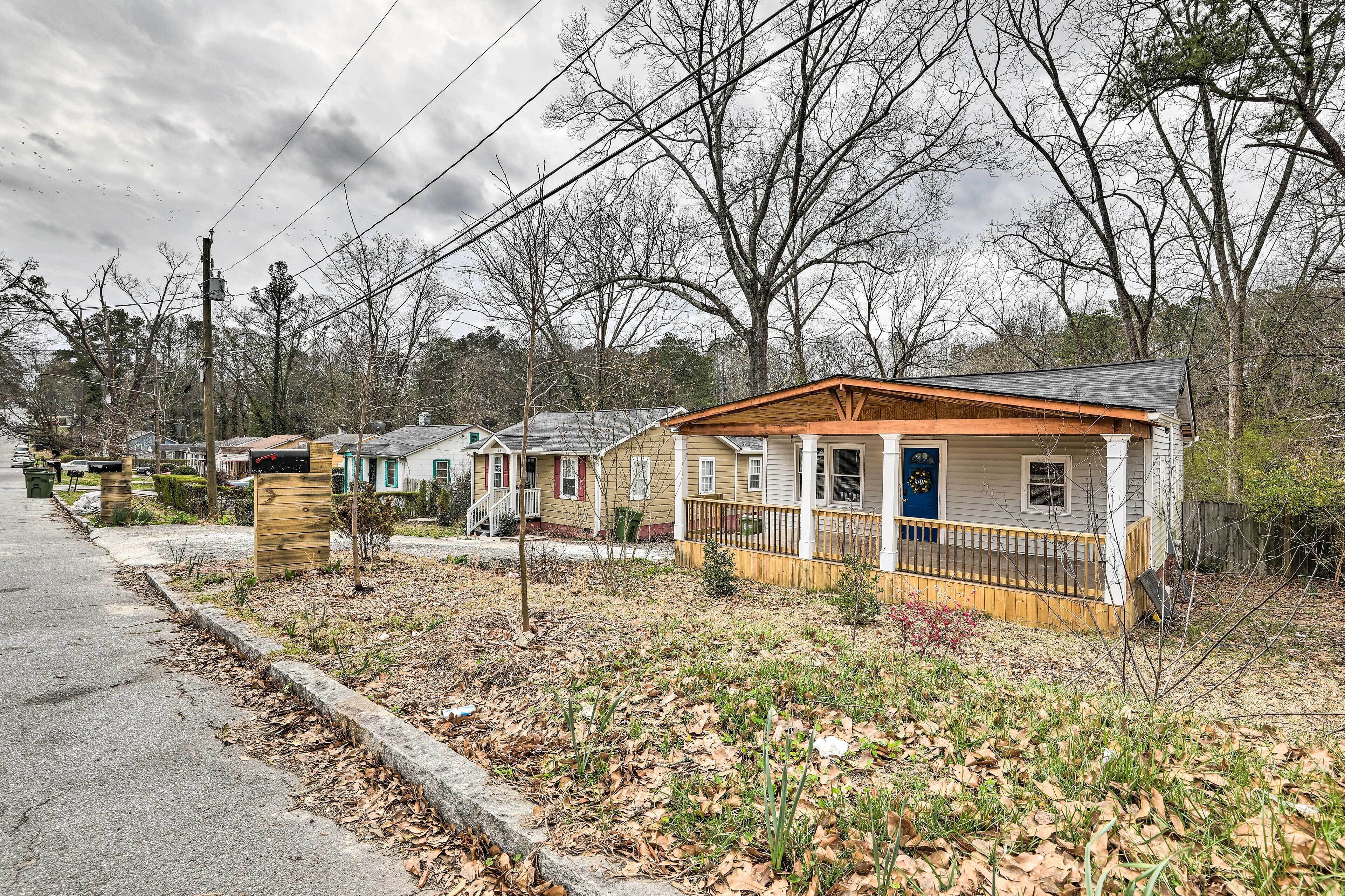 A row of single-story houses with front porches, a sidewalk, and leaf-covered ground.
