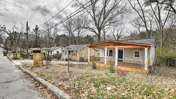 A row of single-story houses with front porches, a sidewalk, and leaf-covered ground.