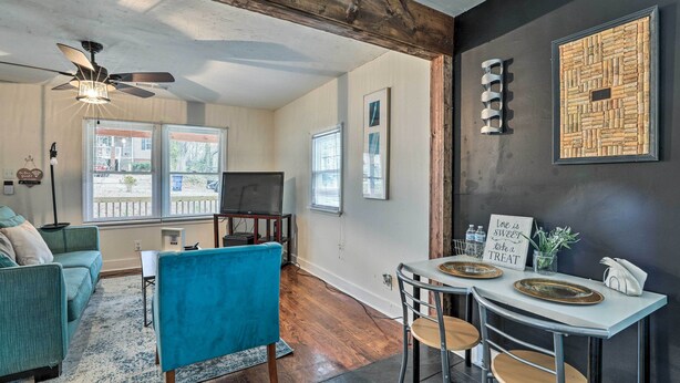 A living room with a blue armchair, a TV, and a ceiling fan. There is a dining area with a table and chairs. - Charming Atlanta Vacation Home ~ 5 Mi to Dtwn (Atlanta)