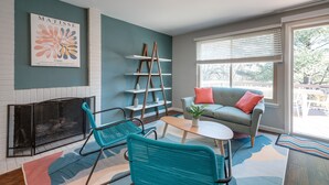 A living room with teal walls, a fireplace, a sofa, and a coffee table. - Modern North Potomac Home w/ Furnished Deck! (Gaithersburg)