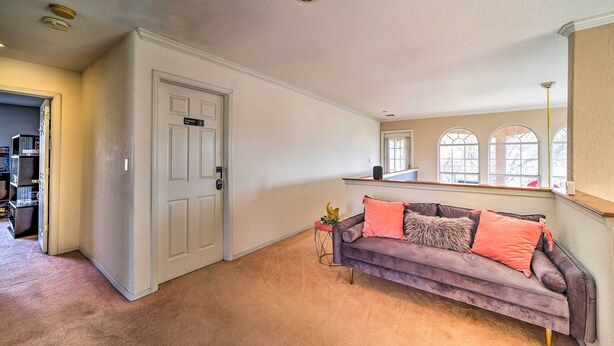 Un salón amplio con un ventanal grande, un sofá morado y una puerta que da a otra habitación.