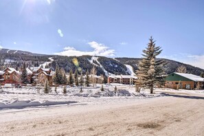A snow-covered landscape with buildings, including a lodge with a green roof and a wooden cabin. - Keystone Condo Near Hiking, Biking & Fun (Keystone)