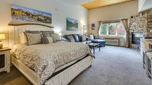 Une chambre avec un grand lit, un canapé, une cheminée et un tableau au mur.