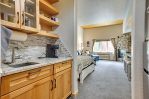 A compact kitchen with a sink, stove, and wooden cabinets.