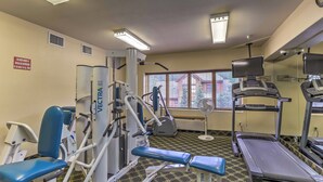 Une salle de sport équipée de matériel d’exercice, d’un tapis de course et d’une fenêtre avec des stores.