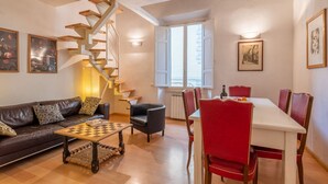 A living room with a sofa, coffee table, chessboard, a dining table with chairs, a staircase, and artwork on the walls. - Modern Murate View in Florence by Mmega (Firenze)