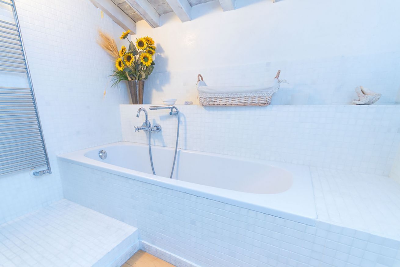Een moderne badkamer met een vrijstaand bad, een handdoekhouder en een rieten mand aan de muur.