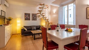 A compact living space with a dining area, a sofa, a staircase, and a kitchen. - Modern Murate View in Florence by Mmega (Firenze)