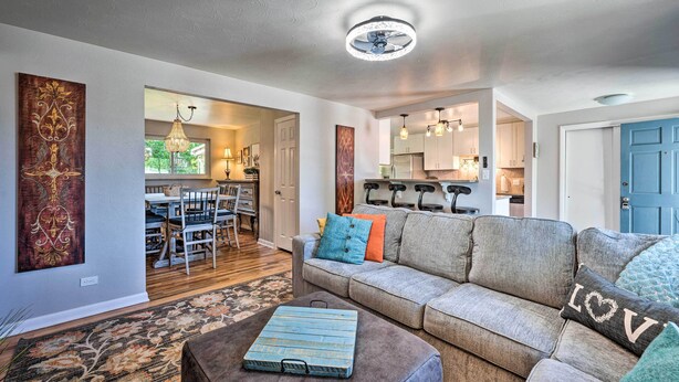 A living room with a grey sofa, a patterned rug, and a blue suitcase on an ottoman. - Fenced Yard + Patio: Pet-friendly Denver Home Base (Arvada)