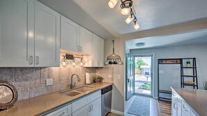 A modern kitchen with white cabinets, granite countertops, and a farmhouse-style light fixture. - Fenced Yard + Patio: Pet-friendly Denver Home Base (Arvada)