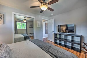 Quarto com cama, ventilador de teto, televisão e mesa consola.