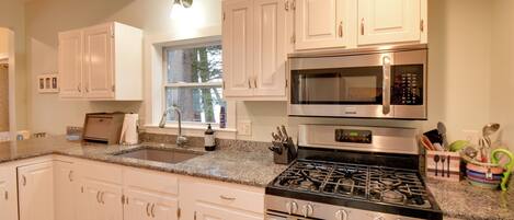 A modern kitchen with white cabinets, stainless steel appliances, and granite countertops.
