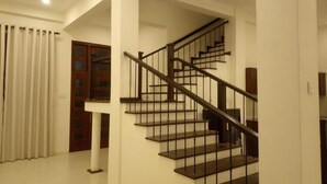 A staircase with a handrail, a landing, and a door with glass panels. - Riverdale Ridge Apartment I (Kandy)