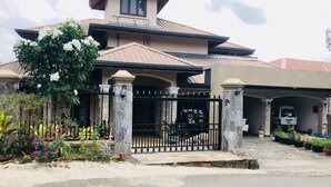 A two-story house with a tiled roof, a gated entrance, and a driveway leading to a garage. - Riverdale Ridge Apartment I (Kandy)