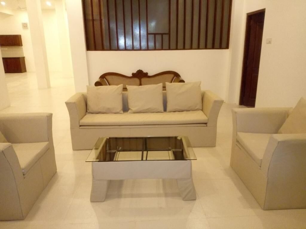 Un salon comprenant un canapé, deux fauteuils et une table basse en verre.