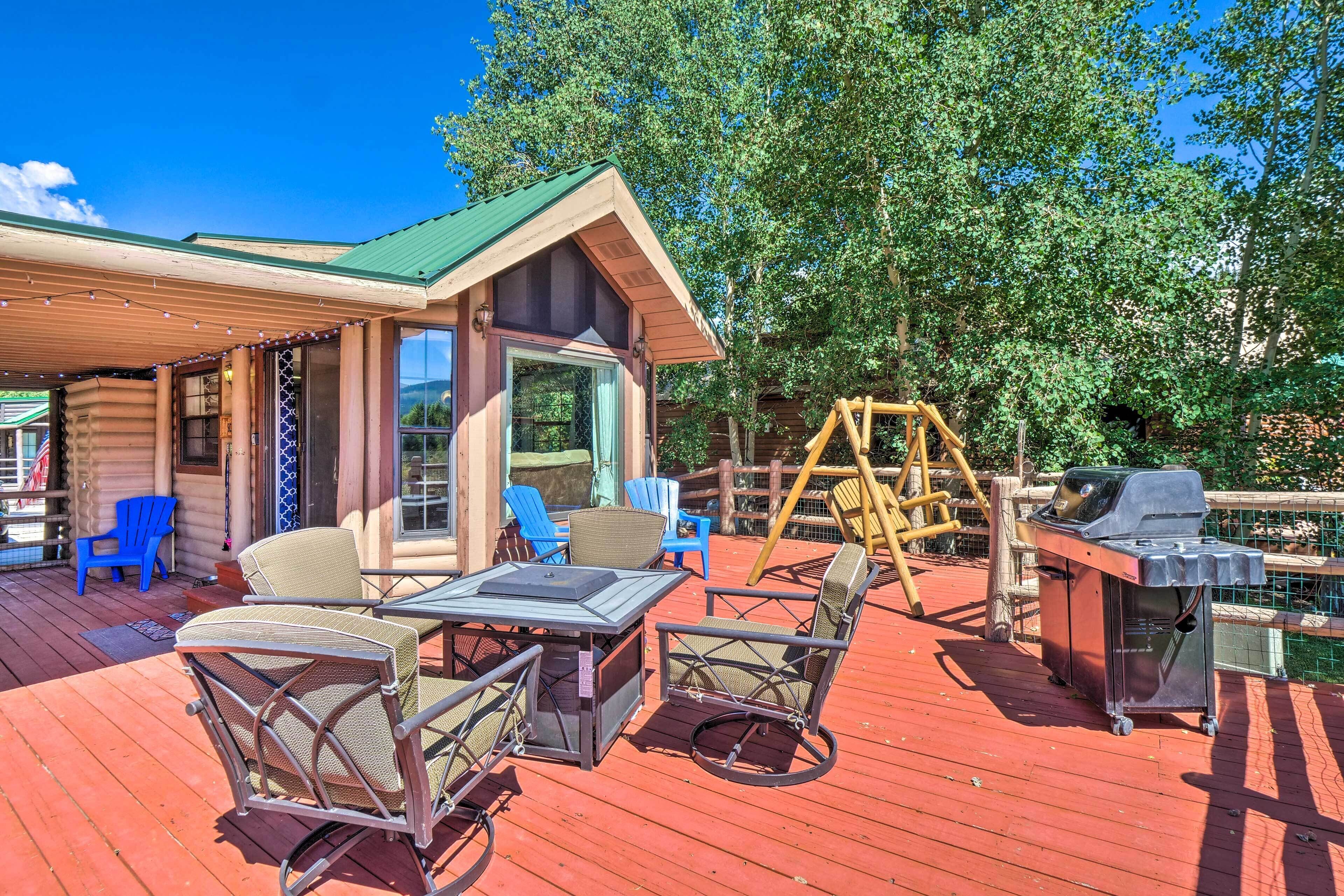 A wooden cabin with a deck, outdoor seating, and a grill.