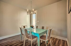 Un comedor con una mesa turquesa, sillas blancas y un candelabro.