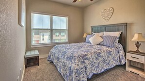 A bedroom with a bed, a nightstand, a ceiling fan, a window, and a heart-shaped wall decoration. - College Station Townhome w/ Furnished Patio! (College Station)