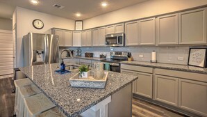 A modern kitchen with granite countertops, stainless steel appliances, and a central island with bar seating. - College Station Townhome w/ Furnished Patio! (College Station)