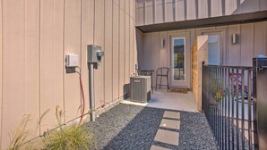 A building exterior with a beige facade, a small outdoor seating area, and a gated entrance. - College Station Townhome w/ Furnished Patio! (College Station)
