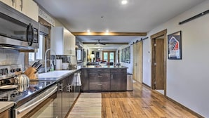 A modern kitchen with a central island, stainless steel appliances, and wooden flooring. - Main Street Frisco Condo w/ Private Patio! (Frisco)
