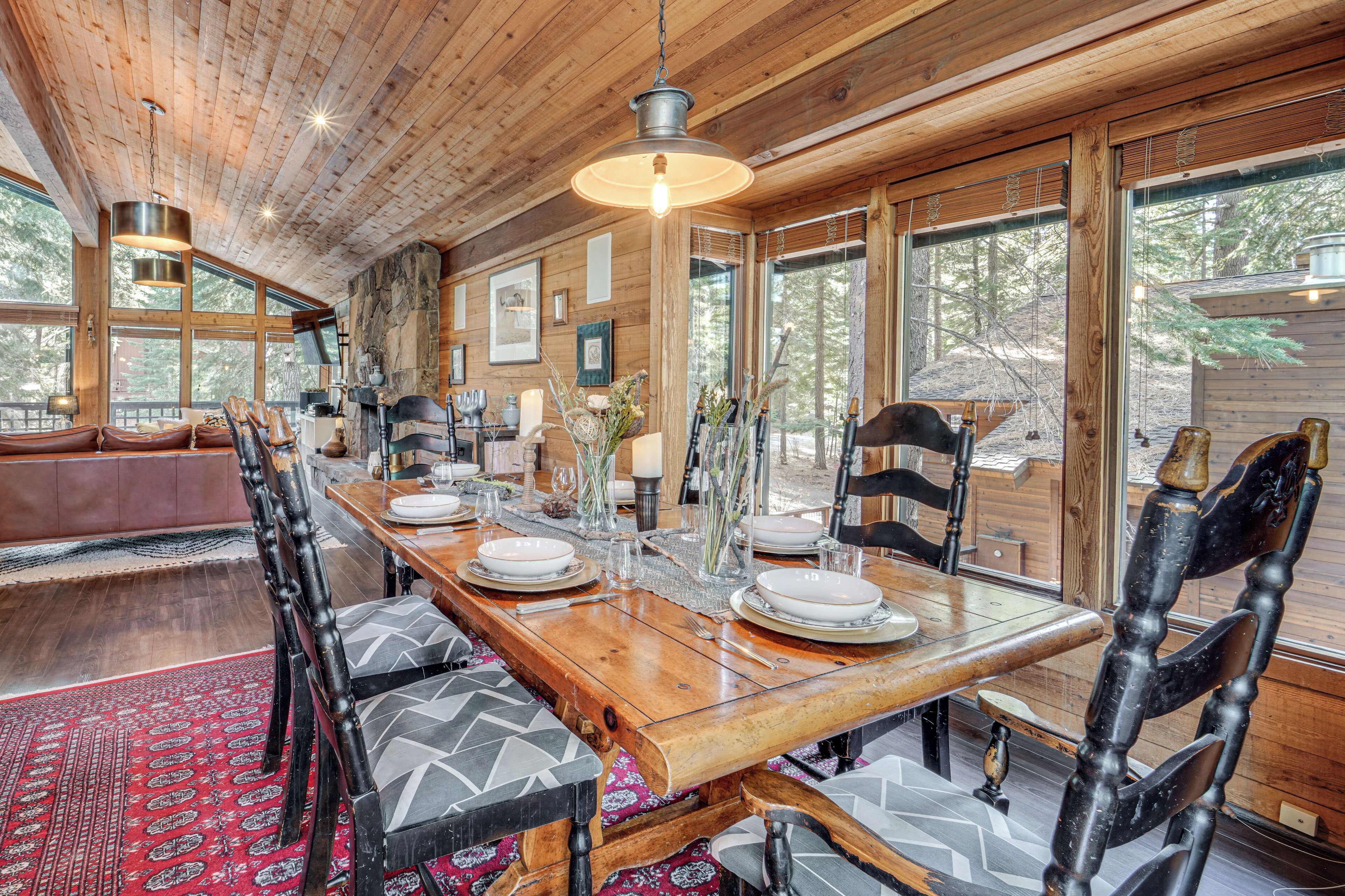 Un coin repas en bois avec une longue table dressée pour quatre personnes, entourée de chaises dotées de coussins à motifs.