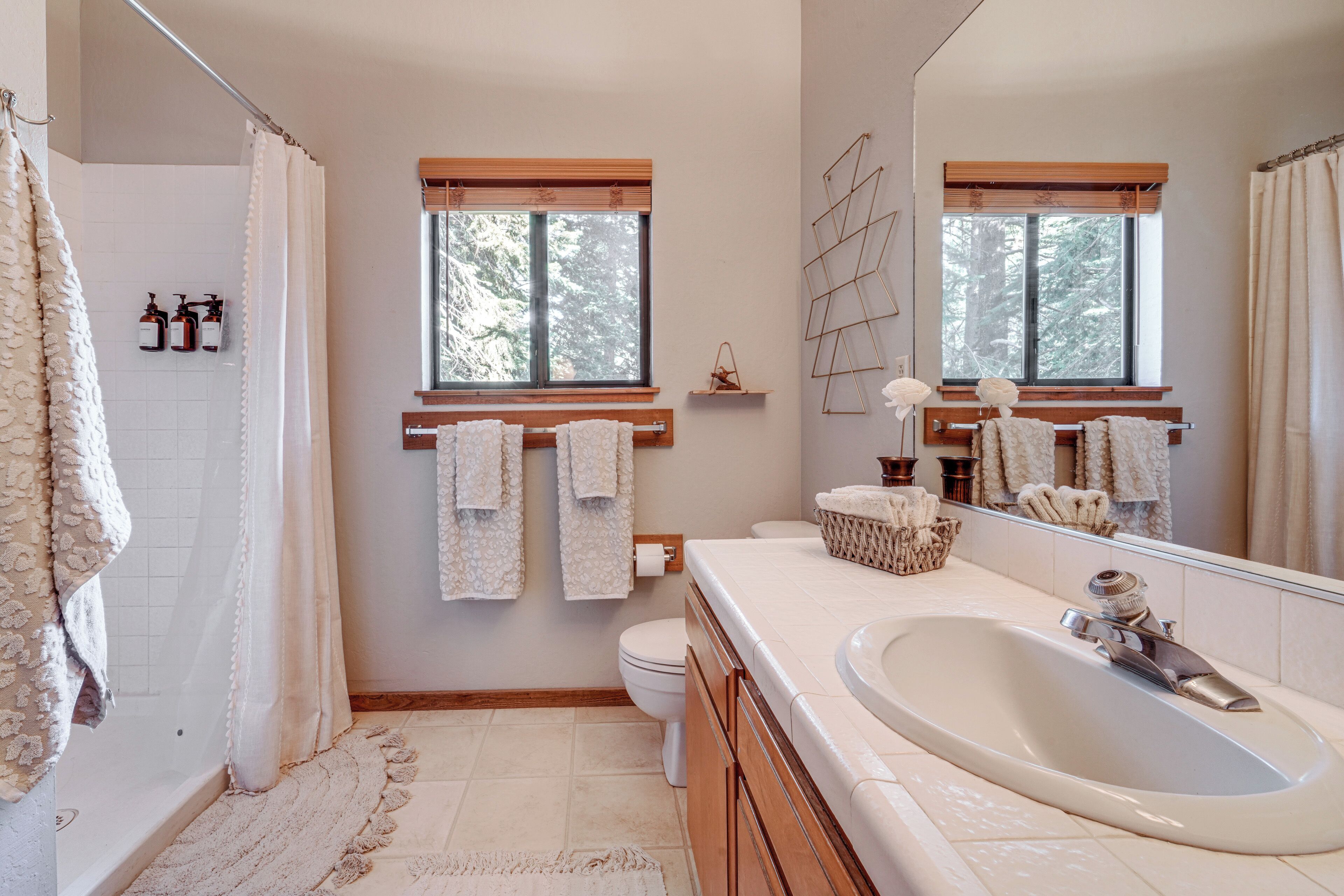 Un baño moderno con bañera, un espejo grande y dos ventanas.