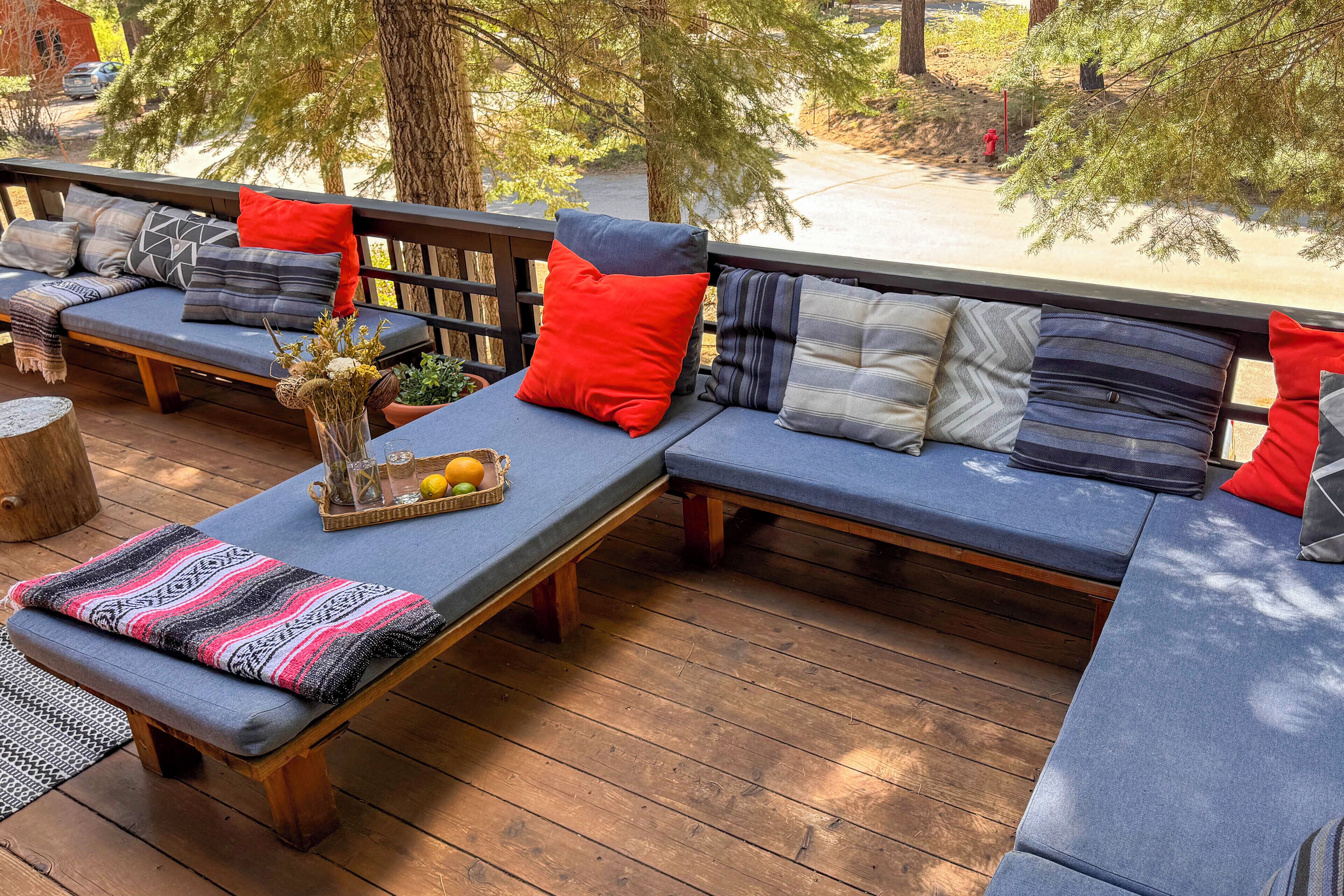 Una terraza de madera con zona de estar integrada, bancos acolchados y cojines.