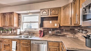 A kitchen with wooden cabinets, a stainless steel dishwasher, and a brick backsplash. - Colorado Springs Home: Game Room, 3 Mi to Downtown (Colorado Springs)