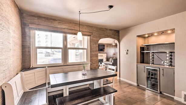 A kitchen with a dark wooden table, white bench seating, a window with a view of the street, and a built-in oven. - Colorado Springs Home: Game Room, 3 Mi to Downtown (Colorado Springs)