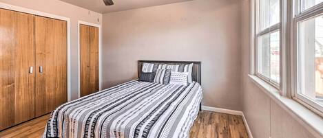 Une chambre à coucher avec un lit, une armoire en bois, un ventilateur de plafond et une fenêtre.