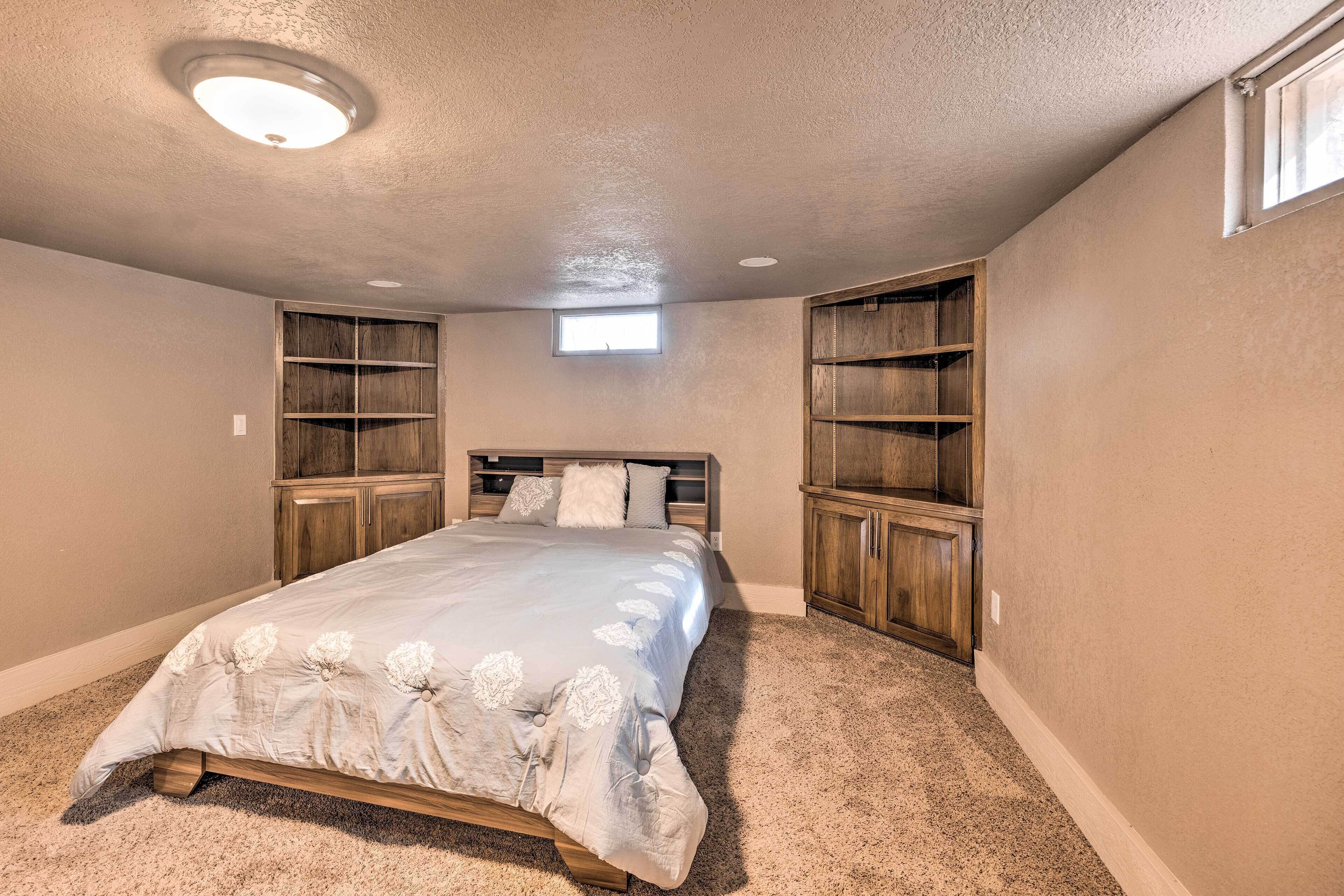 A bedroom with a bed, built-in shelving, and a ceiling light.