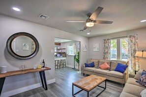 A modern living room with a sofa, coffee table, and a ceiling fan. There is a kitchen area visible in the background. - San Antonio Home ~ 4 Mi to Dtwn + The Pearl! (San Antonio)