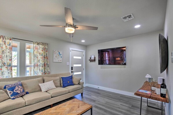 A living room with a sofa, a coffee table, a ceiling fan, and a TV mounted on the wall. - San Antonio Home ~ 4 Mi to Dtwn + The Pearl! (San Antonio)